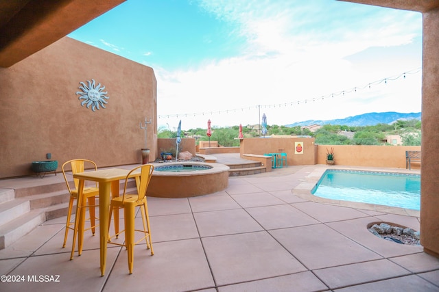 view of swimming pool with a patio, a mountain view, and an in ground hot tub