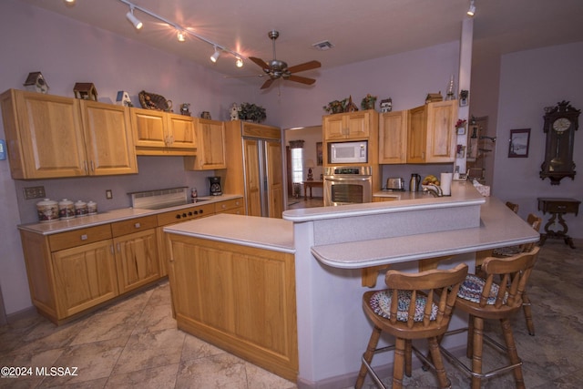 kitchen with built in appliances, a breakfast bar area, kitchen peninsula, light tile patterned flooring, and ceiling fan