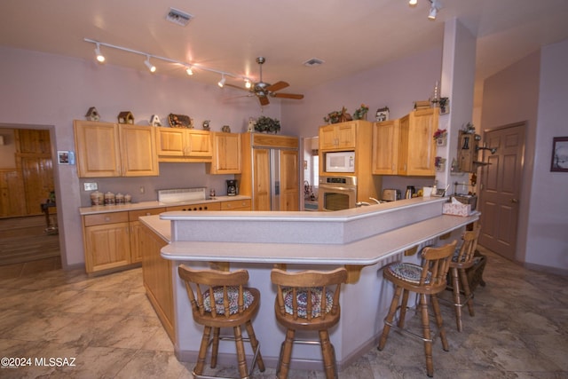 kitchen featuring ceiling fan, oven, a kitchen bar, white microwave, and light tile patterned floors