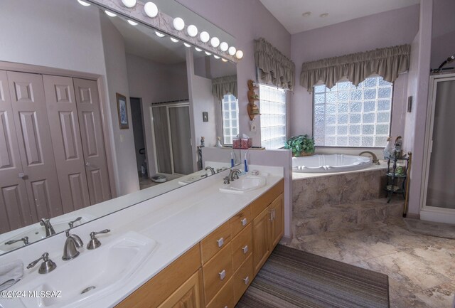 bathroom with double vanity, tiled tub, tile patterned floors, and a wealth of natural light