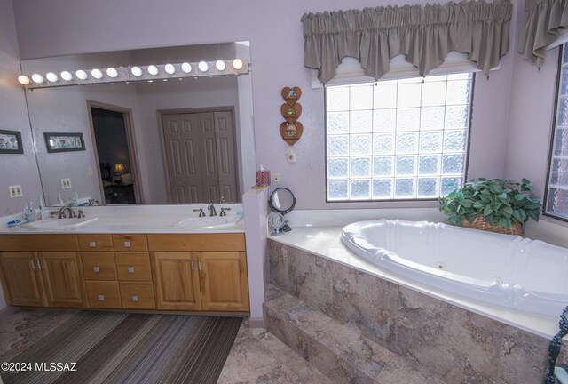 bathroom with dual vanity, tile patterned floors, and a relaxing tiled tub