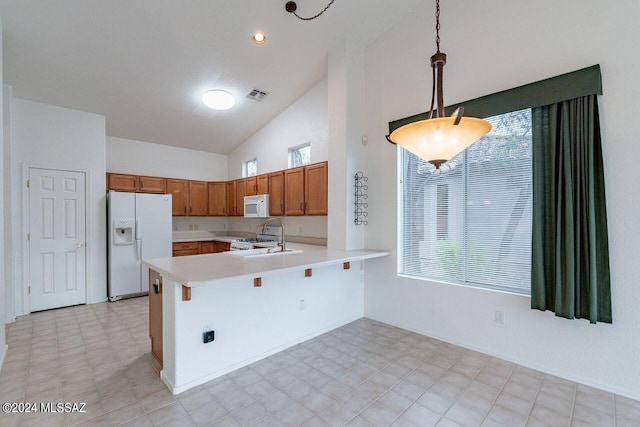 kitchen featuring kitchen peninsula, hanging light fixtures, sink, white appliances, and high vaulted ceiling