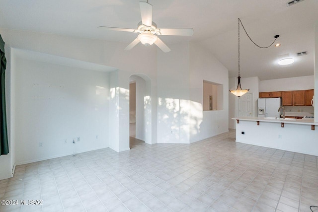 unfurnished living room featuring ceiling fan, sink, and high vaulted ceiling