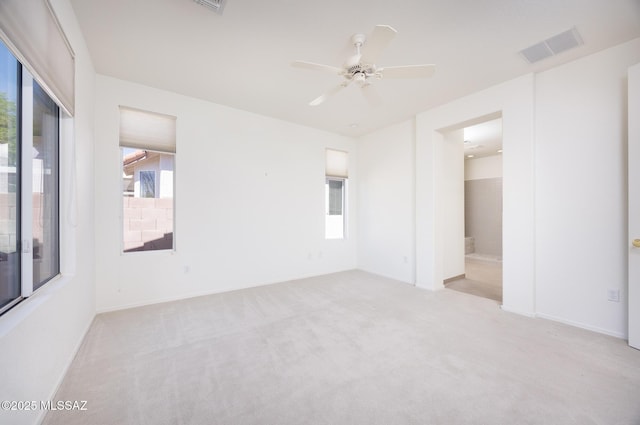 unfurnished bedroom with multiple windows, carpet, ensuite bath, and visible vents