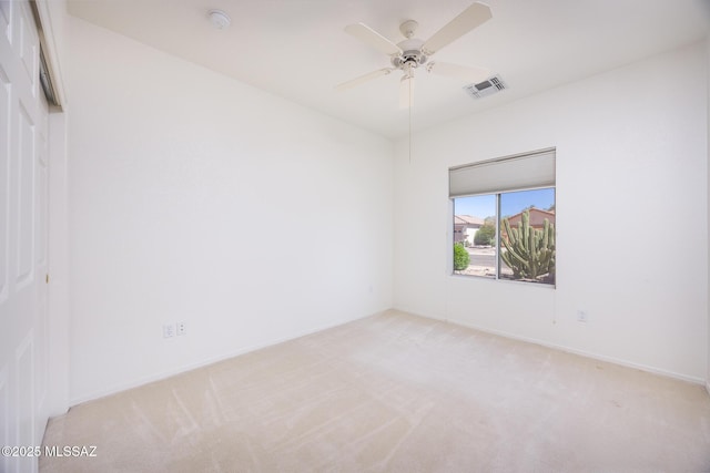 spare room with ceiling fan, visible vents, and light carpet