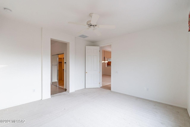 unfurnished bedroom featuring carpet floors, a walk in closet, and ceiling fan