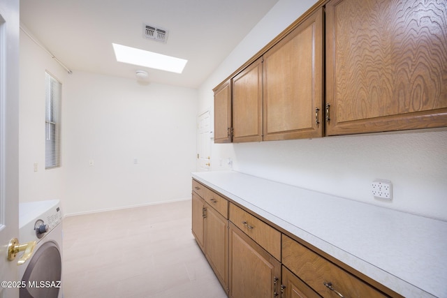 kitchen with visible vents, light floors, washer / clothes dryer, brown cabinets, and a skylight