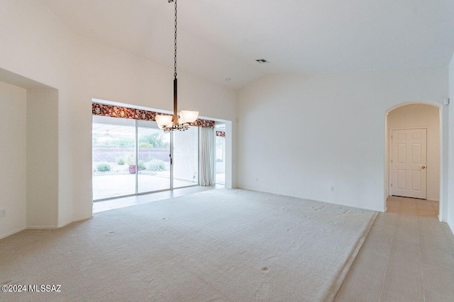 interior space with high vaulted ceiling, light colored carpet, and an inviting chandelier