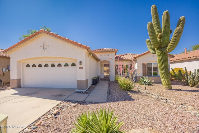 mediterranean / spanish home featuring a garage, stucco siding, concrete driveway, and a tile roof