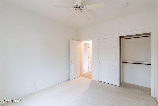 unfurnished bedroom with ceiling fan, light carpet, and a closet