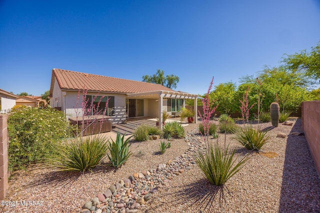 view of front facade featuring a pergola, a hot tub, stucco siding, a patio, and a tiled roof