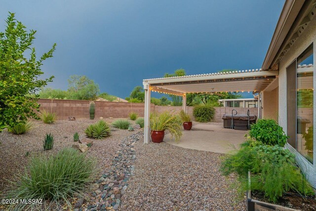 yard at dusk featuring a pergola and a patio area