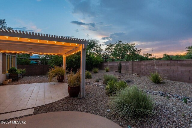 patio terrace at dusk with ceiling fan and a pergola