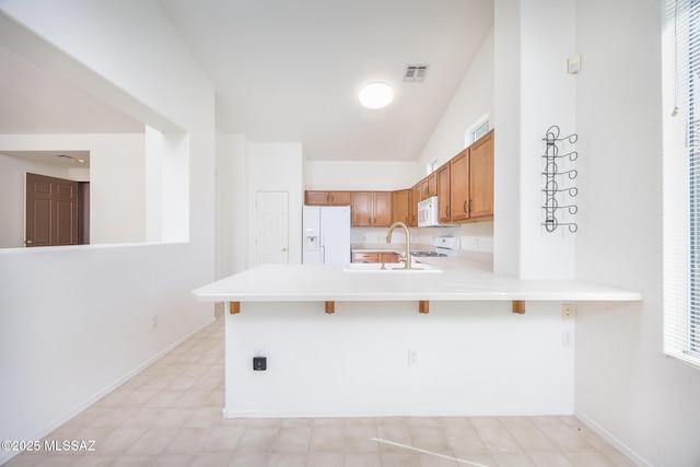 kitchen with a breakfast bar area, visible vents, light countertops, a peninsula, and white appliances