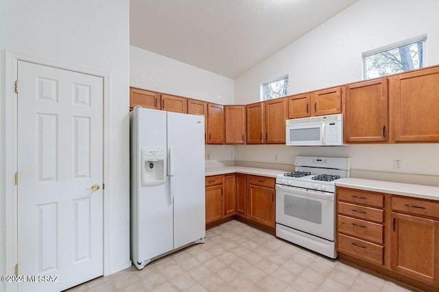 kitchen featuring white appliances and vaulted ceiling