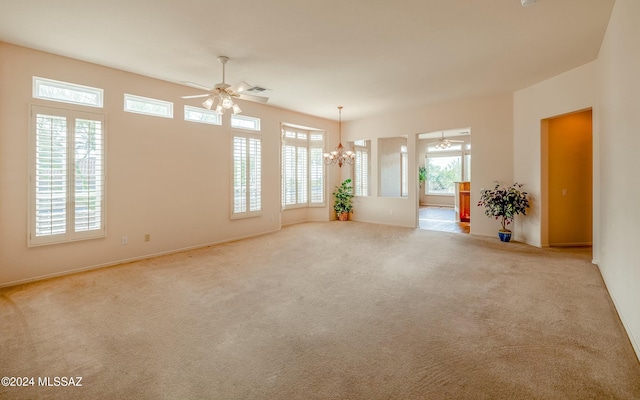 empty room featuring ceiling fan with notable chandelier and light colored carpet