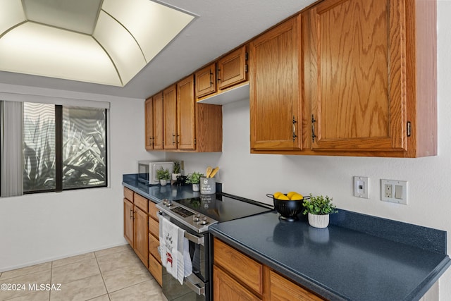 kitchen with light tile patterned floors and stainless steel range with electric stovetop