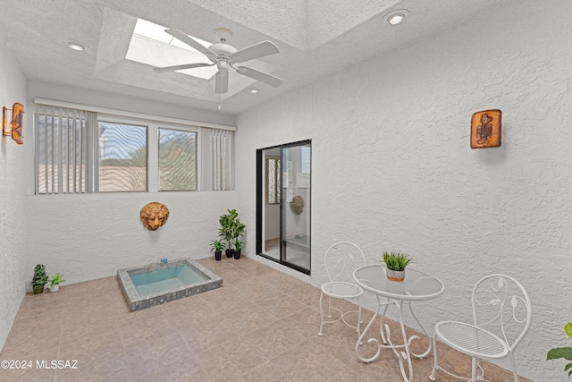 interior space with a jacuzzi, a skylight, and a textured ceiling