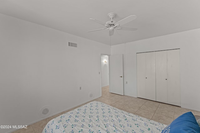 bedroom featuring ceiling fan, a closet, and light tile patterned floors