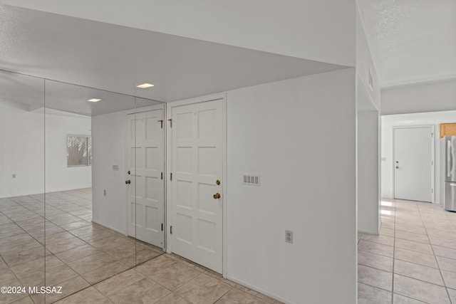 tiled empty room featuring a textured ceiling