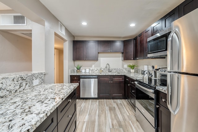 kitchen featuring dark brown cabinetry, stainless steel appliances, sink, and light stone countertops