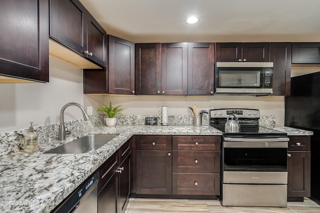 kitchen with light stone counters, sink, stainless steel appliances, and dark brown cabinetry