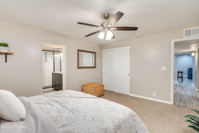 bedroom featuring ceiling fan, a closet, light colored carpet, and connected bathroom