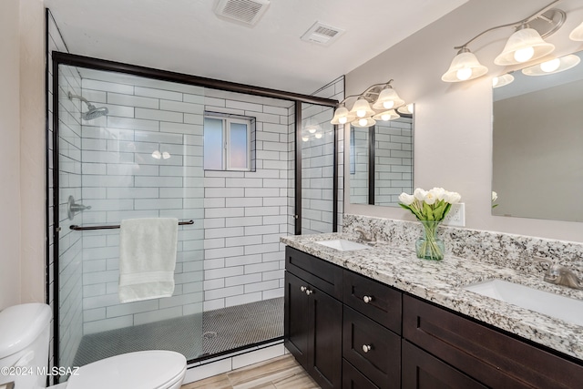 bathroom with dual bowl vanity, walk in shower, and toilet