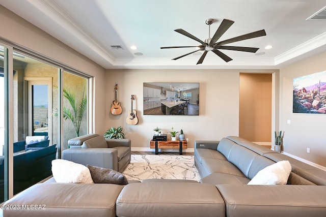 living room featuring a tray ceiling, crown molding, and visible vents