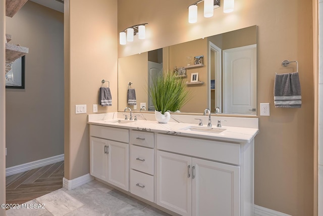 bathroom with double vanity, baseboards, and a sink