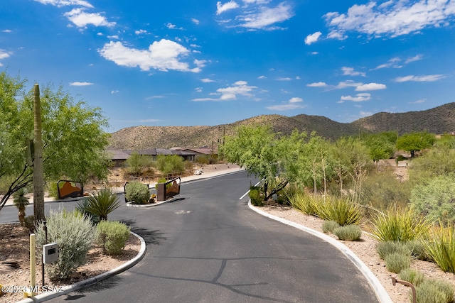 view of road featuring curbs, a mountain view, and a gated entry