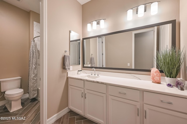 bathroom with vanity, curtained shower, toilet, and baseboards