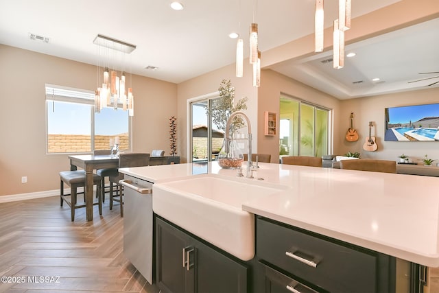 kitchen with a center island with sink, dishwasher, light countertops, and a sink