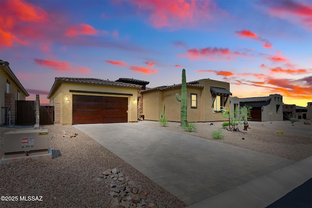 view of front facade with fence, stucco siding, a garage, driveway, and a gate