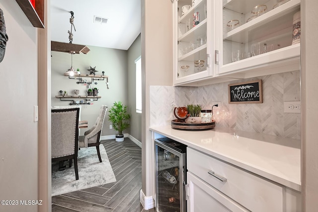 bar featuring visible vents, baseboards, wine cooler, decorative backsplash, and a bar