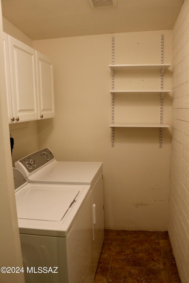 laundry room featuring cabinets, washing machine and dryer, and dark tile patterned floors