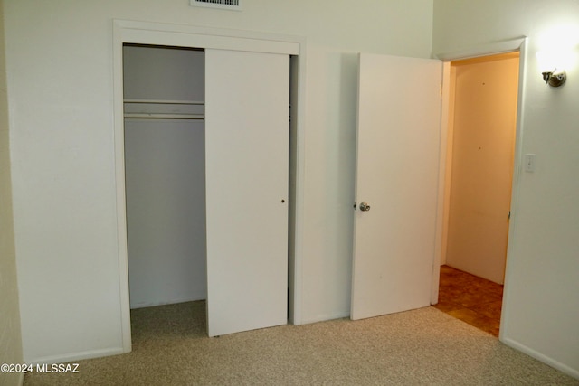 unfurnished bedroom with a closet and light colored carpet