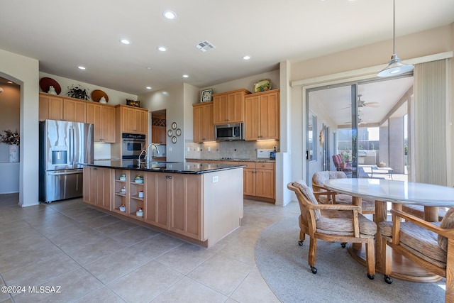 kitchen featuring tasteful backsplash, light tile patterned floors, appliances with stainless steel finishes, an island with sink, and pendant lighting