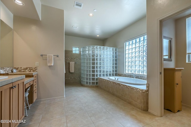 bathroom featuring tile patterned flooring, vanity, decorative backsplash, and independent shower and bath