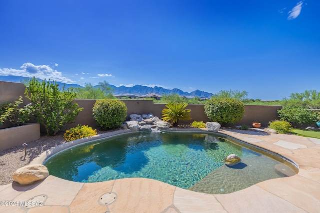 view of swimming pool with pool water feature, a mountain view, and a patio area