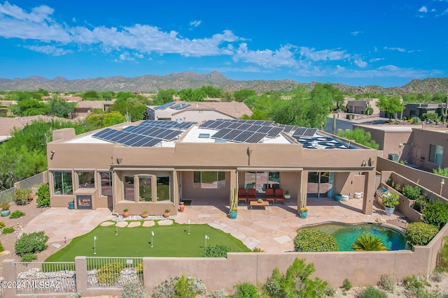 back of house featuring a mountain view, a patio area, and solar panels