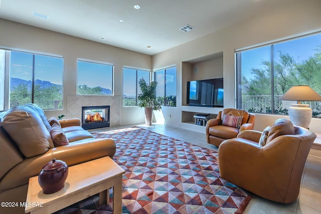 living room with plenty of natural light, a premium fireplace, a mountain view, and tile patterned flooring