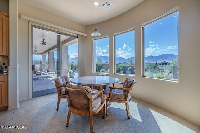 dining room with a mountain view, light tile patterned floors, and a healthy amount of sunlight