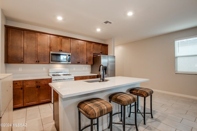 kitchen with stainless steel appliances, a breakfast bar, sink, and an island with sink