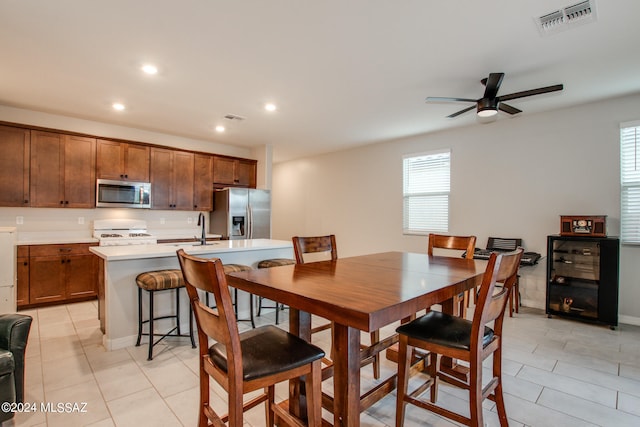 dining space featuring light tile patterned floors, sink, and ceiling fan