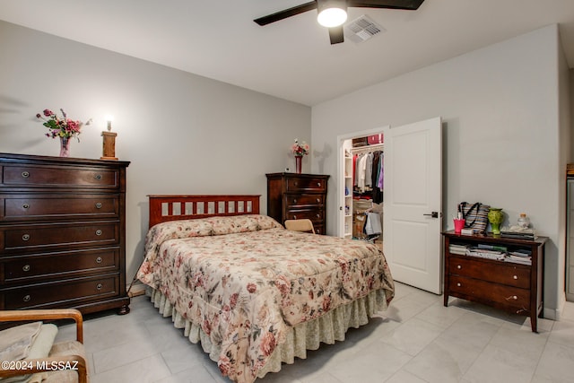 tiled bedroom featuring a closet, ceiling fan, and a walk in closet