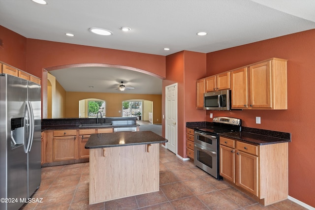 kitchen featuring ceiling fan, a center island, tile patterned flooring, stainless steel appliances, and sink