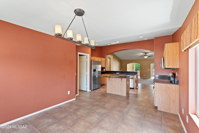 kitchen featuring ceiling fan with notable chandelier, hanging light fixtures, stainless steel fridge with ice dispenser, light tile patterned flooring, and a center island