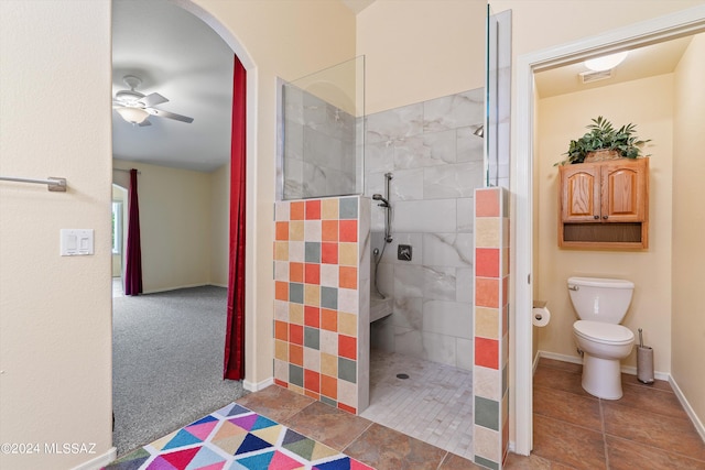 bathroom with ceiling fan, a tile shower, tile patterned flooring, and toilet