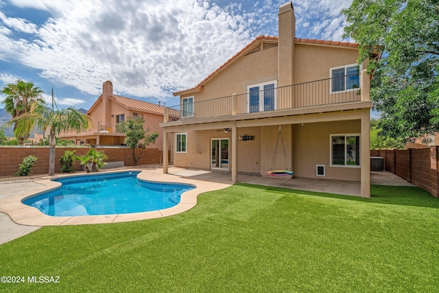 back of property featuring a fenced in pool, a balcony, a yard, and a patio area